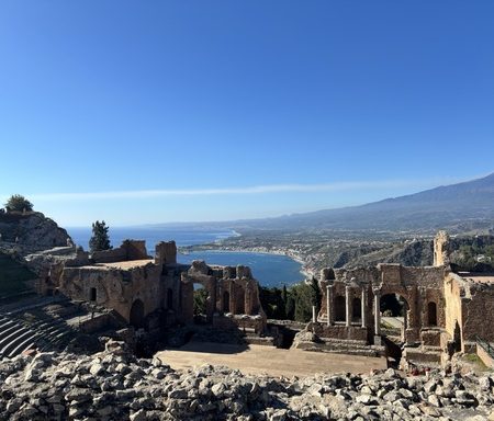 Panoramic view of Taormina with the Greek Theatre, Mount Etna, and coastline during a sightseeing tour